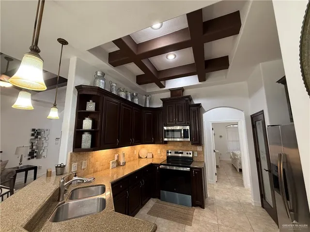 a kitchen with stainless steel appliances kitchen island granite countertop a refrigerator and a sink