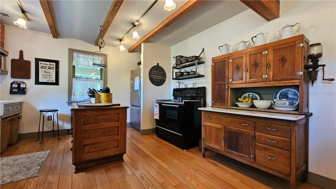 585 Buttermilk Road Hellertown, PA 18055 - Photo 11 of 82 Exposed wood beams accentuate the warm tones of the hardwood flooring, complementing vintage cabinetry and modern appliances.
