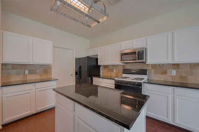 a kitchen with kitchen island granite countertop a sink stainless steel appliances and white cabinets