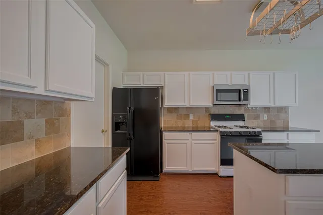 a kitchen with granite countertop white cabinets and stainless steel appliances