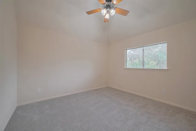an empty room with a chandelier fan and windows