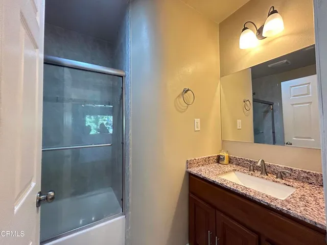 a bathroom with a granite countertop sink mirror and shower