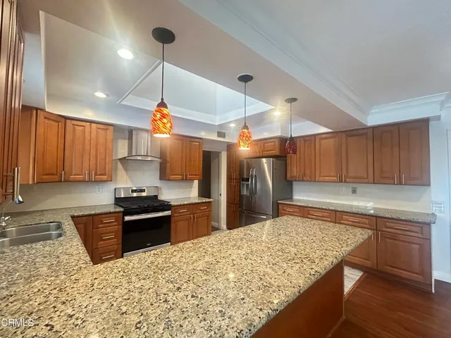a kitchen with stainless steel appliances kitchen island granite countertop a sink stove and refrigerator
