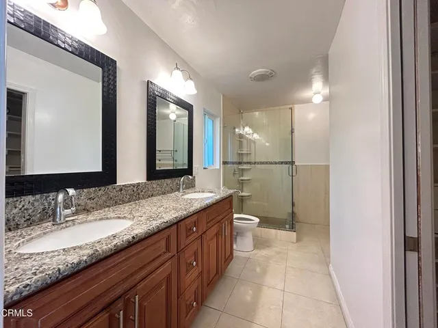 a bathroom with a granite countertop sink a toilet a mirror and shower