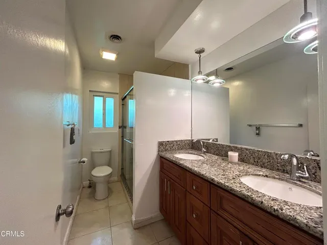 a bathroom with a granite countertop sink a toilet and a large mirror