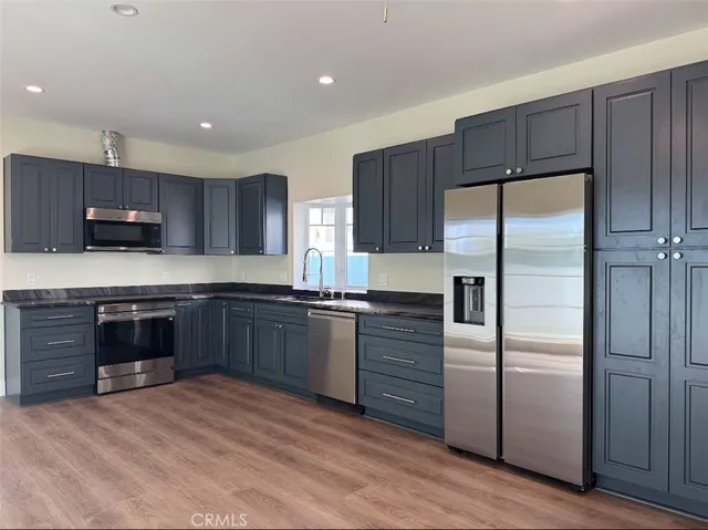 a kitchen with stainless steel appliances kitchen island granite countertop a refrigerator stove and sink