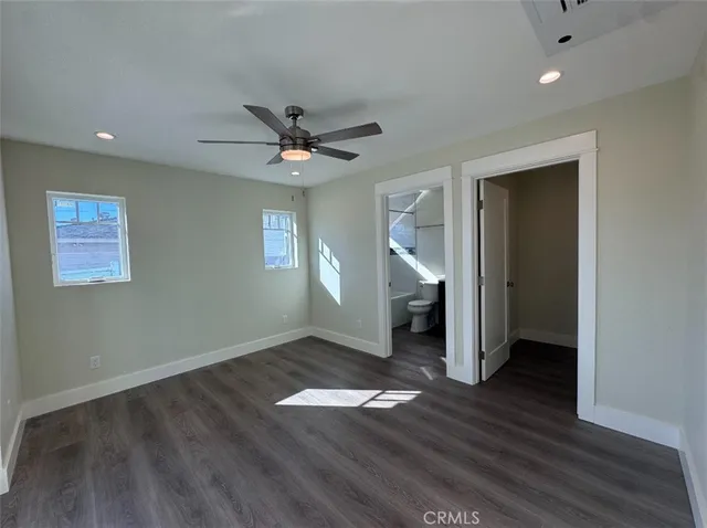 an empty room with wooden floor and a ceiling fan