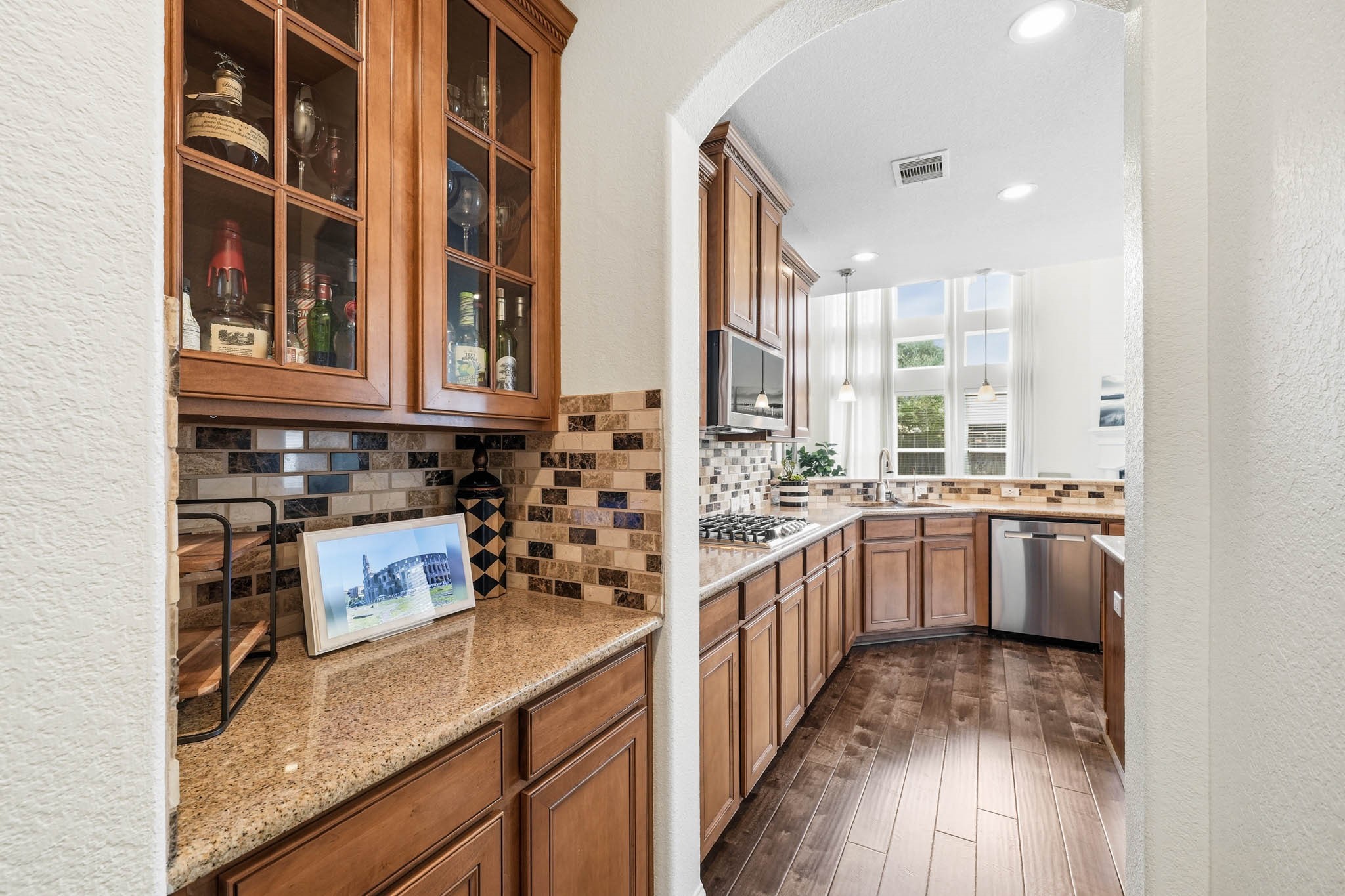 17610 Strackfield Lane Tomball, TX 77377 - Photo 15 of 50 Granite countertops and glass-front cabinetry elevate the butler’s pantry, providing a sophisticated setting for entertaining essentials and organized storage.