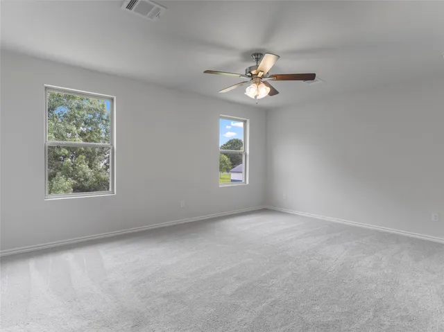 an empty room with windows and fan