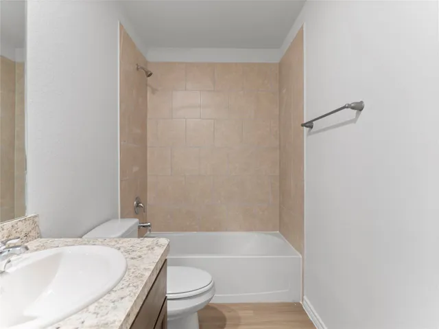 a bathroom with a granite countertop bathtub shower sink vanity and toilet