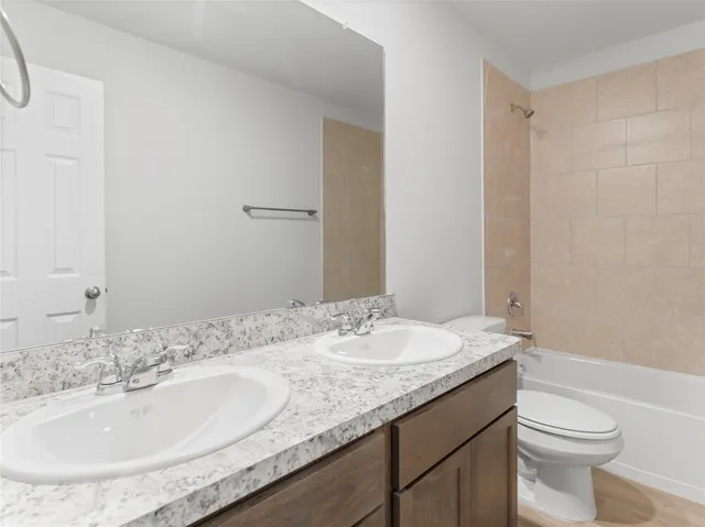a bathroom with a granite countertop sink a toilet and a mirror