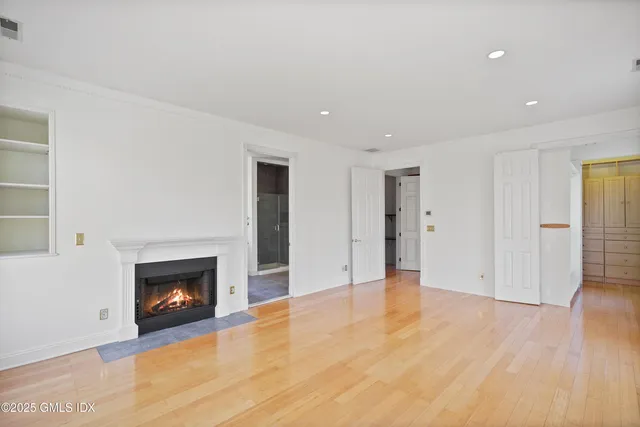 a view of an empty room with wooden floor fireplace and a window