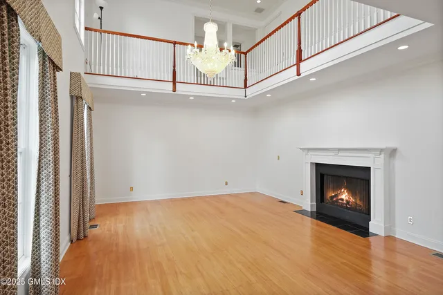 a view of an empty room with wooden floor a fireplace and a window