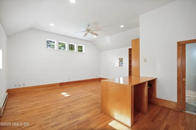 a view of an empty room with a window and wooden floor