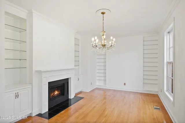 a view of a livingroom with a fireplace a chandelier and wooden floor