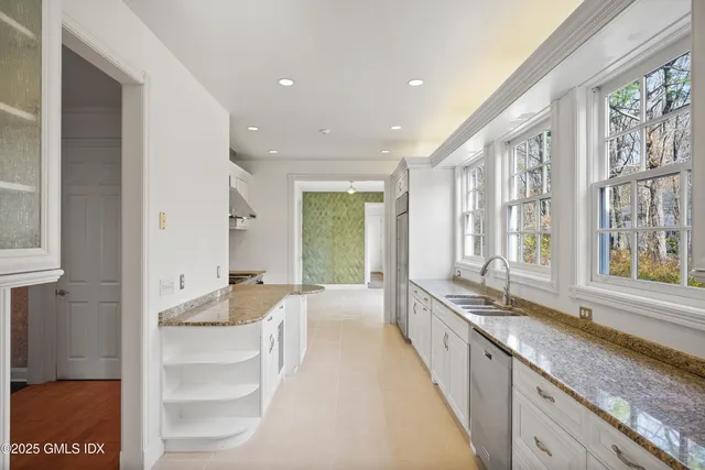 a large white kitchen with granite countertop a large window