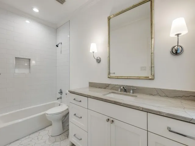 a bathroom with a granite countertop toilet a sink and a mirror