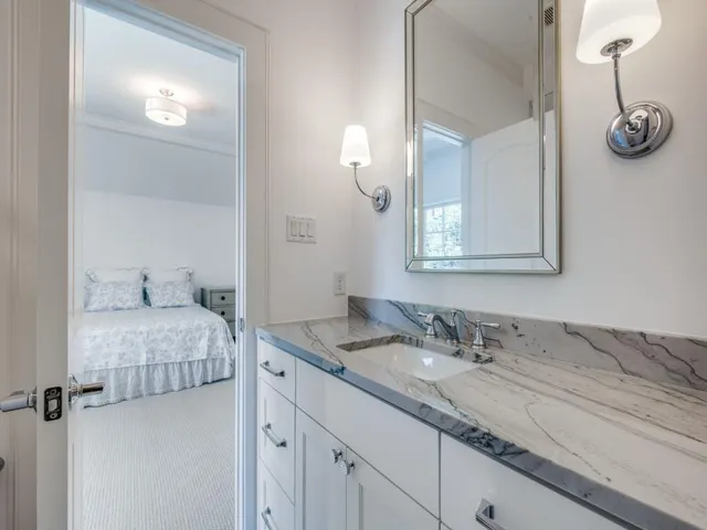 a en suite bathroom with a granite countertop sink and a mirror