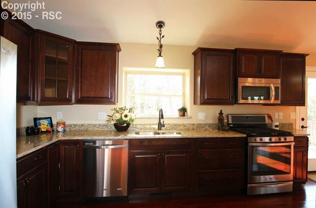 11420 Teachout Road Colorado Springs, CO 80908 - Photo 7 of 36 Kitchen is beautifully appointed with stainless steel appliances, granite and custom cabinetry. Gas range/oven and kitchen pantry with etched glass door.