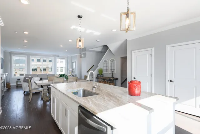 a kitchen with stainless steel appliances granite countertop a sink dishwasher and a dining table with wooden floor