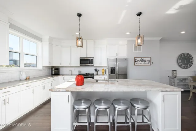 a open kitchen with stainless steel appliances granite countertop a sink a stove a refrigerator and chairs