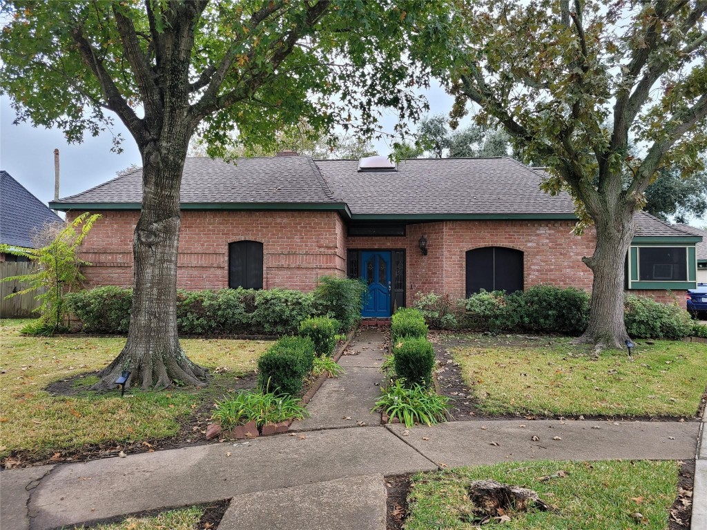 14834 La Rana Drive Houston, TX 77083 - Photo 1 of 14 Sturdy masonry home featuring elegant arched windows, mature shade trees, and a vibrant blue entry door for standout curb appeal.