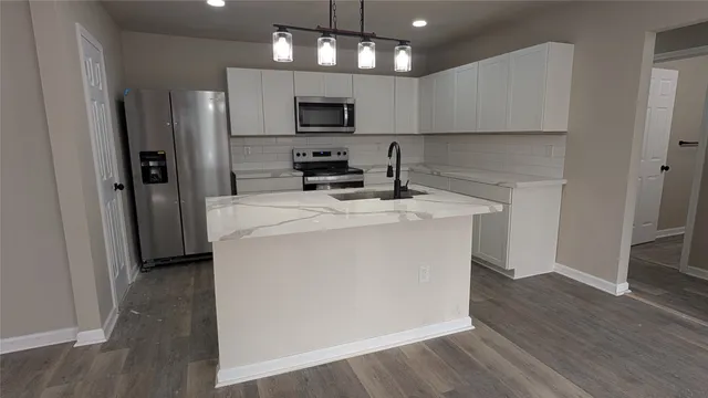 a kitchen with kitchen island a sink stainless steel appliances and cabinets