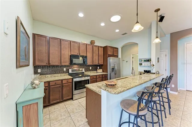 a view of a kitchen island a chandelier and living room in it