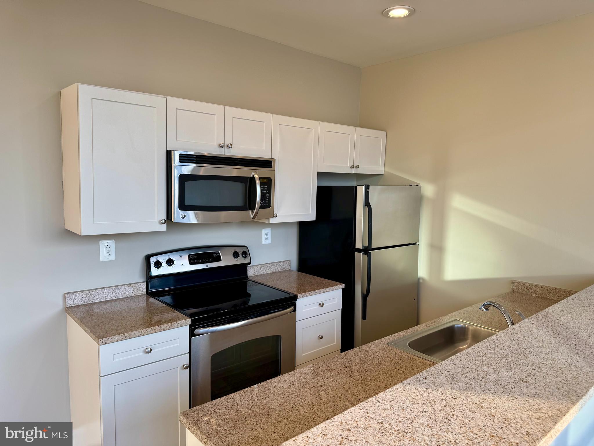 2040 Market Street, Unit 312 Philadelphia, PA 19103 - Photo 5 of 12 a kitchen with stainless steel appliances granite countertop a stove a refrigerator and a microwave