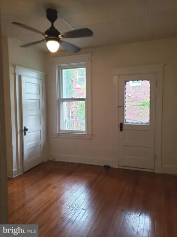 an empty room with wooden floor fan and windows