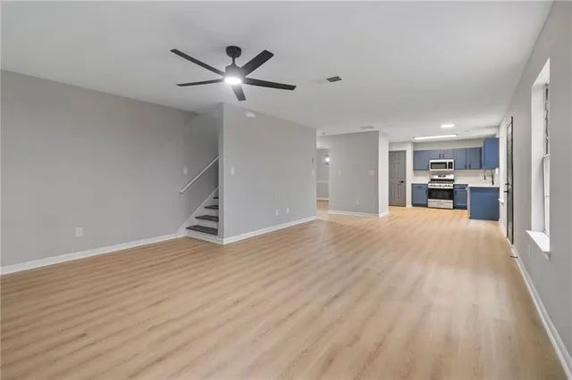 a view of a livingroom with a ceiling fan wooden floor and a ceiling fan
