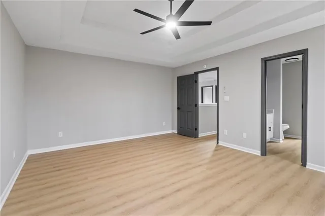 an empty room with wooden floor and ceiling fan