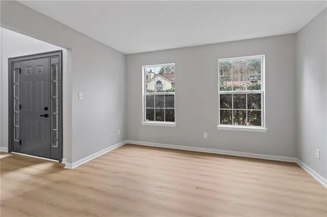 a view of an empty room with wooden floor and windows