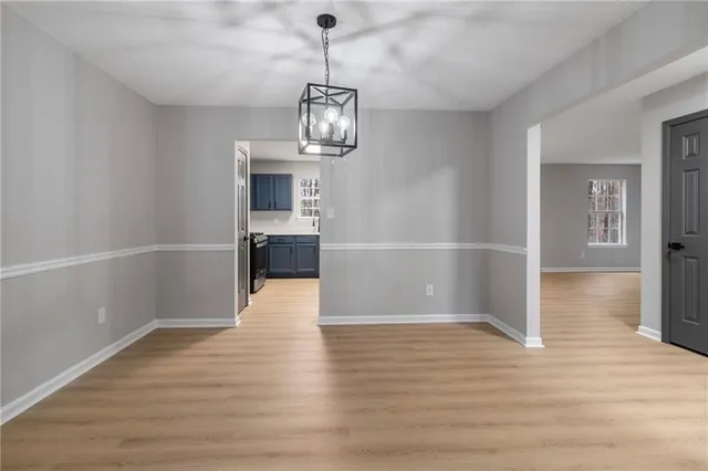 a view of empty room with wooden floor and kitchen view