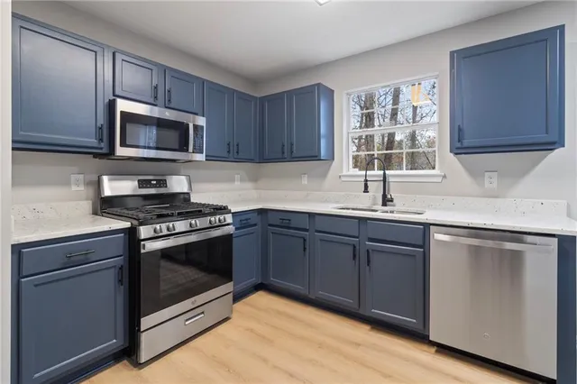 a kitchen with stainless steel appliances granite countertop a sink dishwasher a stove and a microwave oven with cabinets