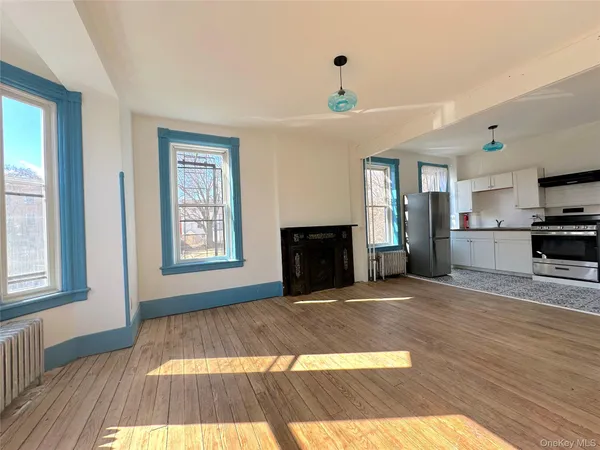 a view of empty room with kitchen and window