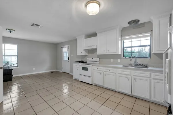 a kitchen with white cabinets a sink a window and appliances