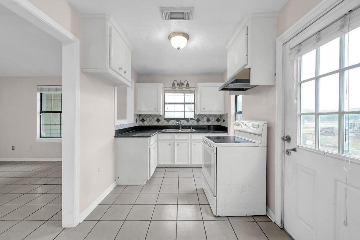 7644 Spring Cypress Road Spring, TX 77379 - Photo 17 of 28 a kitchen with white cabinets a sink a window and appliances