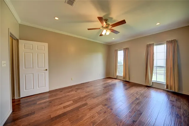 a view of an empty room with wooden floor and window
