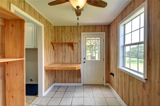 a view of an empty room with window and chandelier fan