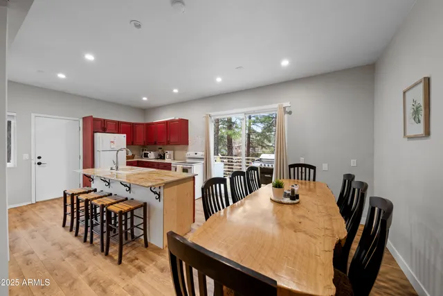 a kitchen with stainless steel appliances granite countertop a stove top oven a dining table and chairs with wooden floor