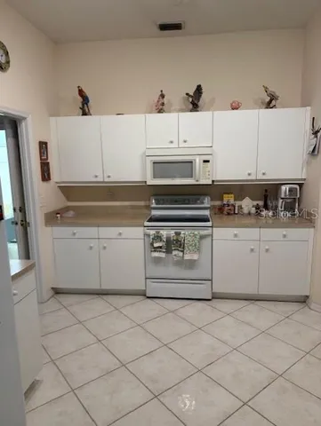 a kitchen with white cabinets and appliances