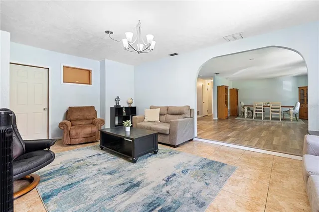 a living room with furniture a chandelier and a flat screen tv