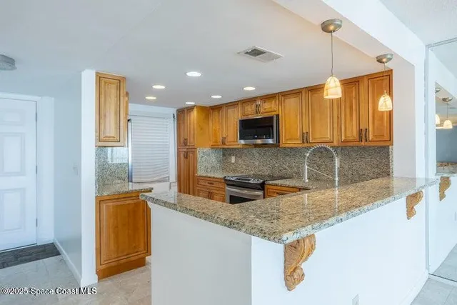 a kitchen with stainless steel appliances granite countertop a sink stove microwave and refrigerator