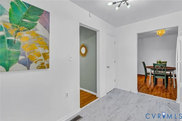 a view of a hallway to room with furniture and wooden floor