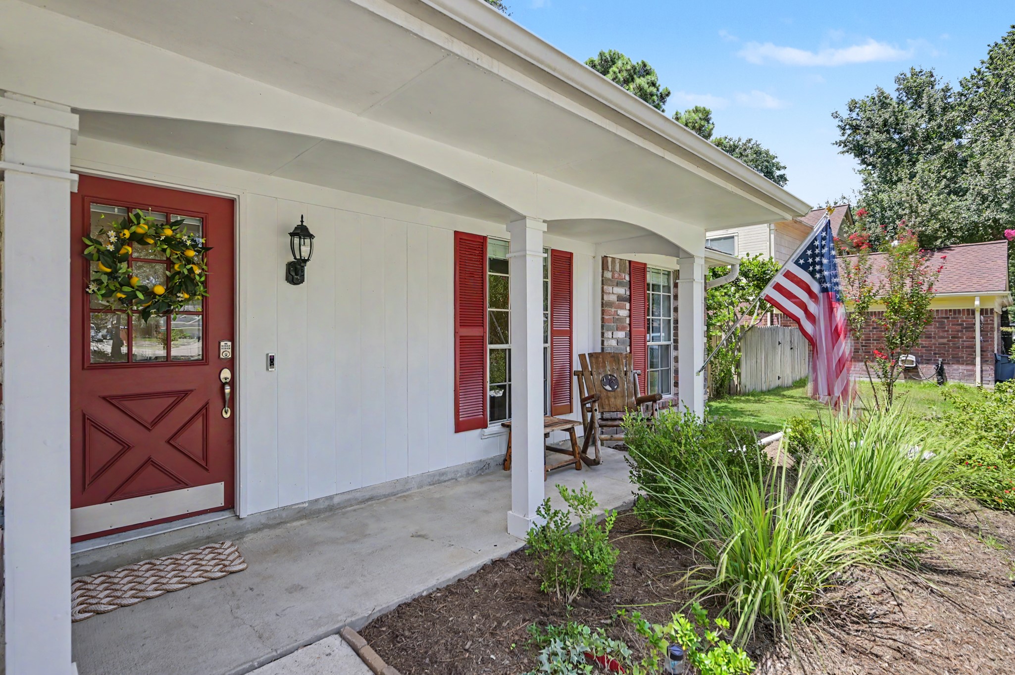 17019 Fordingbridge Court Spring, TX 77379 - Photo 3 of 26 Welcome home to a charming, inviting front porch where classic Southern character meets timeless American pride. The covered entryway features crisp white columns, a welcoming red front door accented with a seasonal citrus wreath, and traditional red shutters that add warmth and character. A proudly displayed American flag completes the picture, creating a welcoming and patriotic first impression.