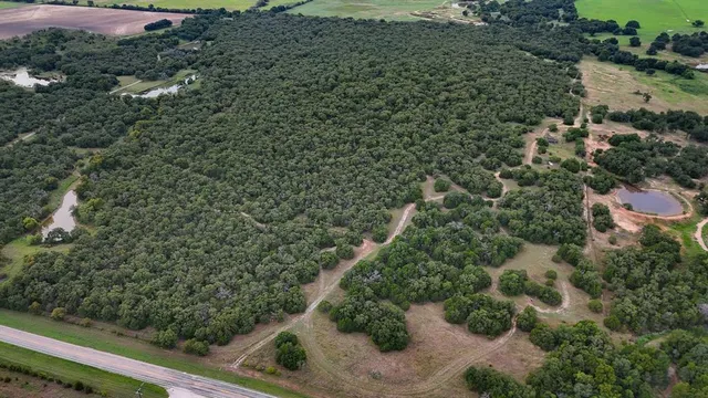 an aerial view of residential house with outdoor space and trees all around