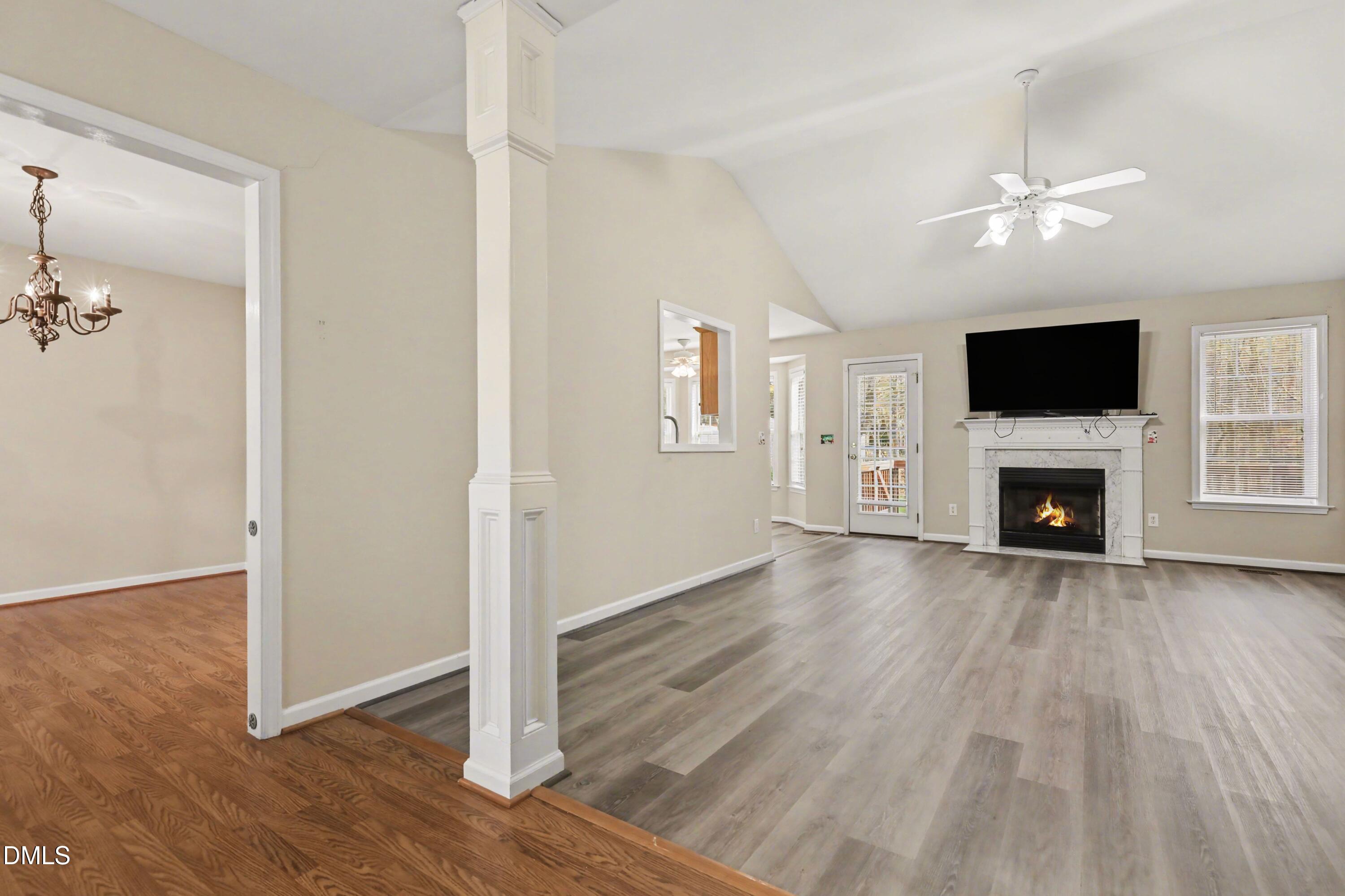390 Eagle Stone Ridge Youngsville, NC 27596 - Photo 5 of 29 an empty room with wooden floor a ceiling fan a fireplace and windows