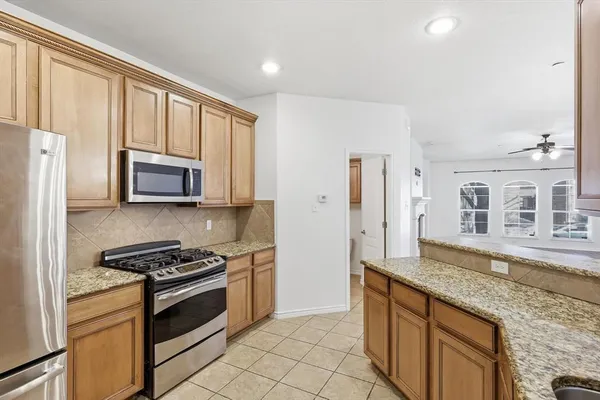 a kitchen with granite countertop a refrigerator stove and cabinets