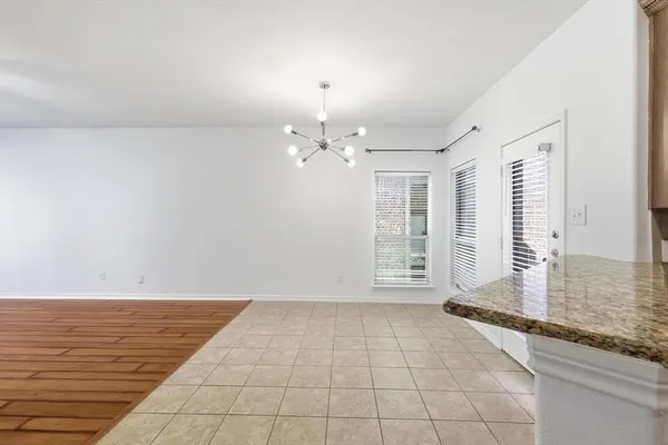 a view of an empty room with window and chandelier fan